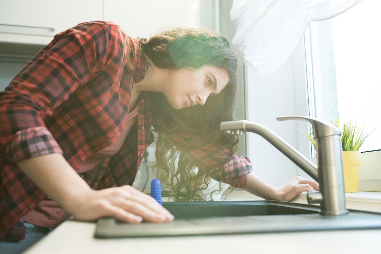 woman in need of emergency plumber looking at faucet that is not working